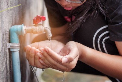 hands of a young woman watering the old water faucet.